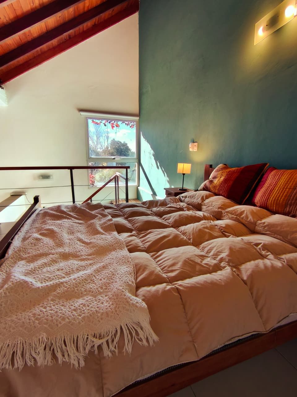Cama Queen en semipiso con ventana al arbolado